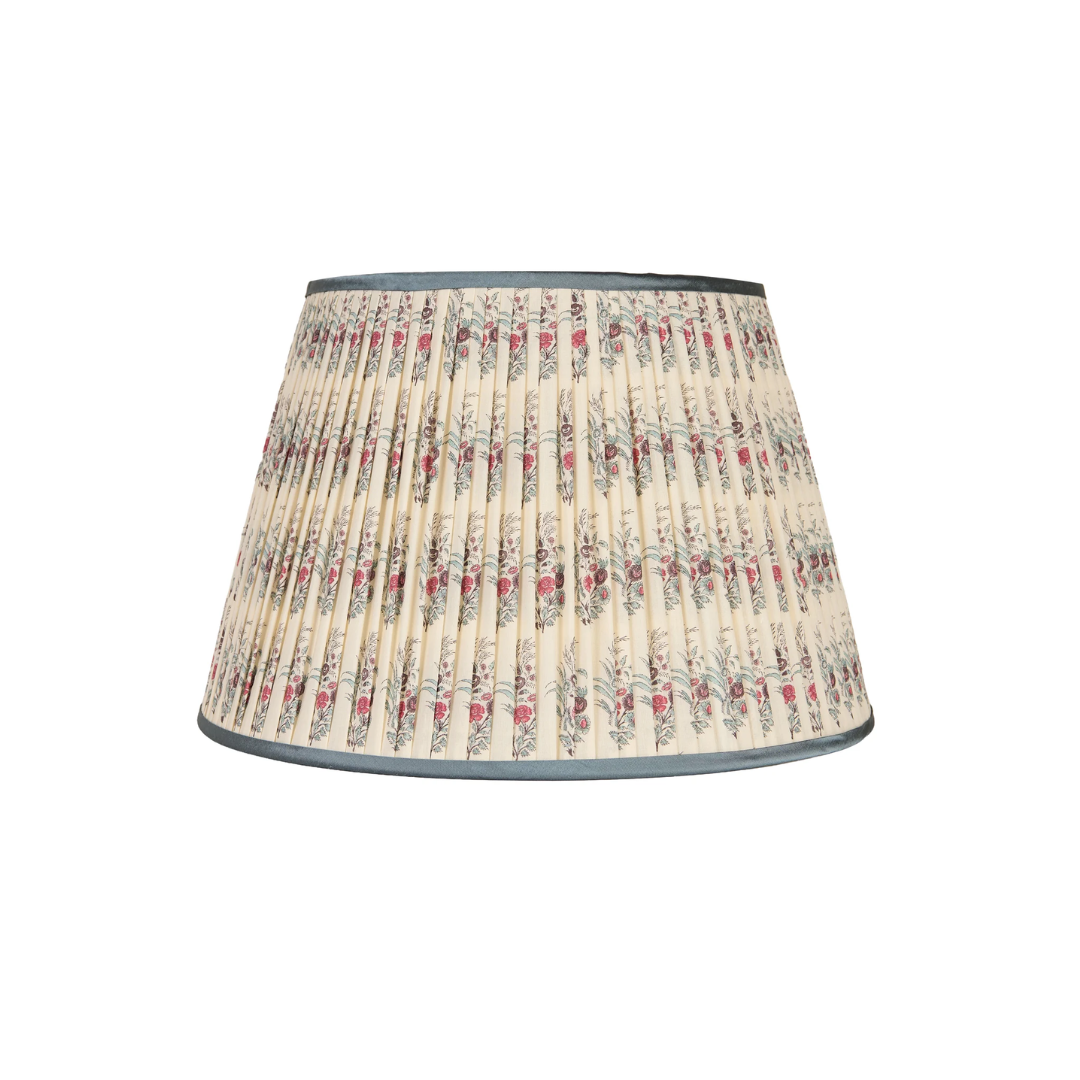 A penny morrison pleated fabric lampshade with a vintage floral pattern on a cream background, featuring gray and red details, finished with a dark gray trim.